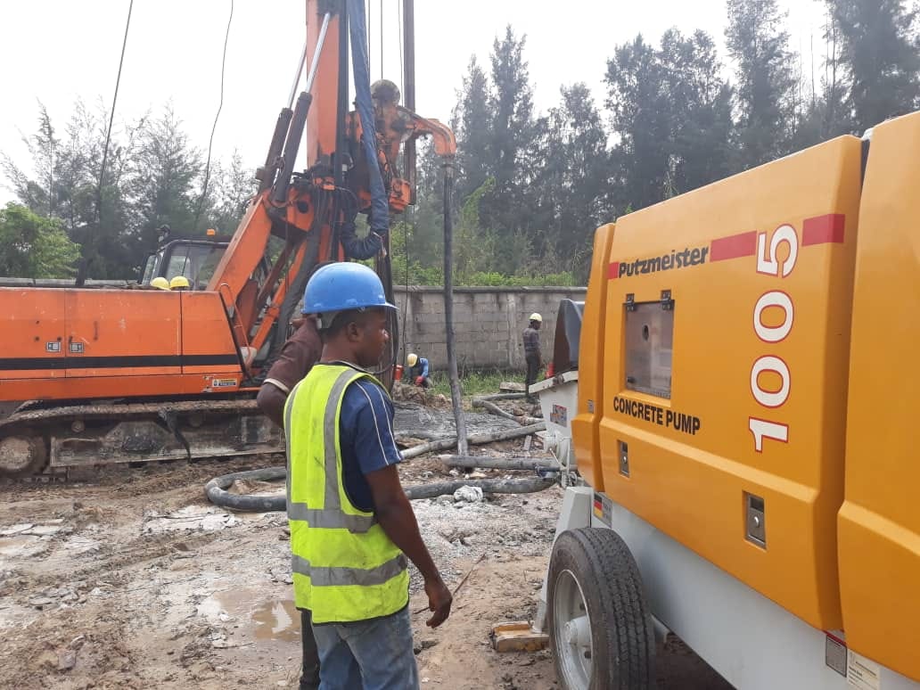 Site engineer beside a Putzmeister concrete pump feeding a piling rig
