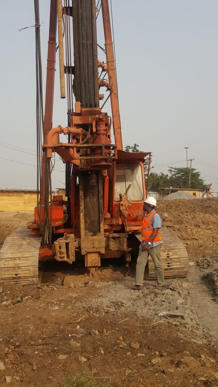 Piling rig set up on a cleared site with an engineer inspecting the works