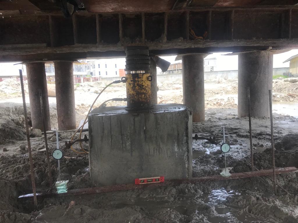 Hydraulic jack and dial gauges mounted under a reaction beam on a test pile head