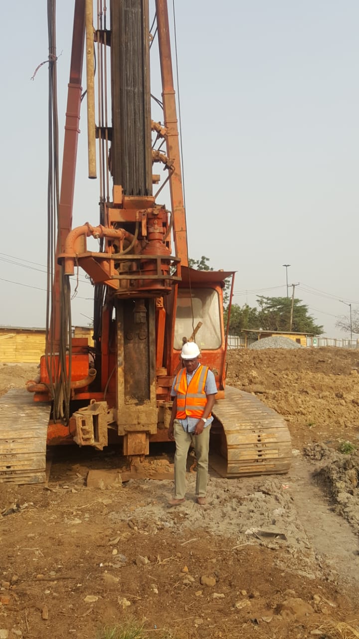 Site engineer in hi-vis standing beside a rotary piling rig at a pile position
